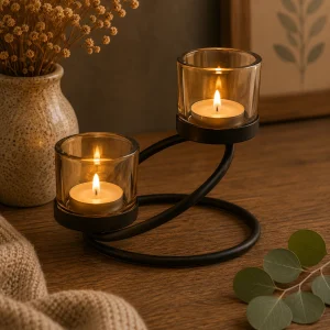 Centrepiece Iron Votive Candle Holder – 2 Cup Double Step with two softly glowing tealight candles in amber glass holders on a black metal stand, displayed on a rustic wooden table in a warm, calming slow living interior.