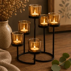 Centrepiece Iron Votive Candle Holder – 6 Cup Circle Tree with six softly glowing tealight candles in amber glass holders on a black metal stand, displayed on a rustic wooden table in a warm, calming slow living interior.