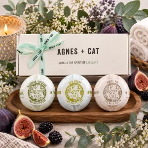 Agnes + Cat Berry & Fig Bath Fizzer Gift Set displayed in a luxury presentation box with Rhubarb Rhubarb, Sea Berry and White Fig bath fizzers, surrounded by fresh figs, blackberries, eucalyptus, soft towels and a glowing candle in an elegant spa-inspired slow living setting.