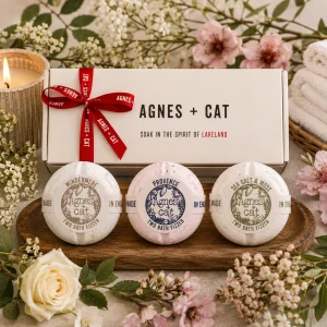 Agnes + Cat Lakeland Favourites Bath Fizzer Gift Set displayed in a luxury presentation box with Windermere, Provence and Sea Salt & Moss bath fizzers, surrounded by fresh flowers, soft towels and a glowing candle in an elegant spa-inspired slow living setting.