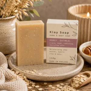 Klay Soap – Honey Oatmeal displayed on a ceramic soap dish with rolled oats, a drizzle of honey, soft linen and eucalyptus, creating a warm spa-inspired bathroom scene in natural light with a cosy slow living atmosphere.