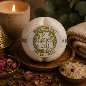 Moroccan Roll luxury bath fizzer by Agnes + Cat displayed on a rustic wooden tray with dried rosebuds, botanical bath salts, a Moroccan-style lantern, soft linen and a glowing candle in a warm spa-inspired slow living setting.