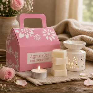 Tea & Roses Home Fragrance Gift Set displayed on a rustic wooden table with a ceramic wax melt burner, scented wax melts, a glowing tealight, fresh pink roses and soft linen in a calming slow living setting.