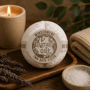 Windermere luxury bath fizzer by Agnes + Cat displayed on a rustic wooden tray with dried lavender, bath salts, soft linen and a glowing candle in a calming spa-inspired slow living setting.